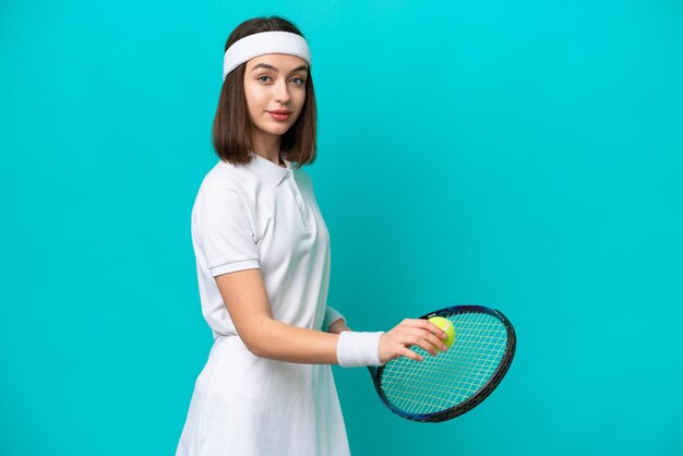 テニスをしている青い背景に分離された若いウクライナの女性