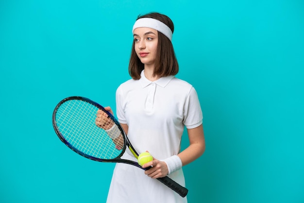 テニスをしている青い背景に分離された若いウクライナの女性