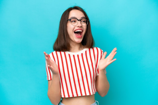 Young Ukrainian woman isolated on blue background with surprise facial expression