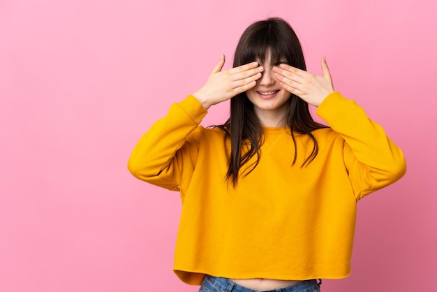 young ukrainian woman isolated on pink background covering eyes by hands and smiling