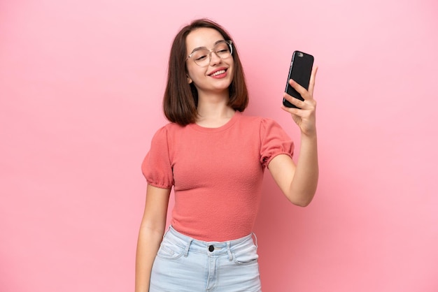 Young Ukrainian woman isolated on pink background making a selfie