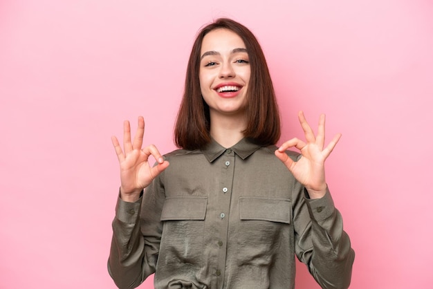 Young Ukrainian woman isolated on pink background showing ok sign with two hands