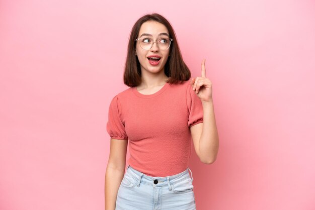 Young Ukrainian woman isolated on pink background thinking an idea pointing the finger up