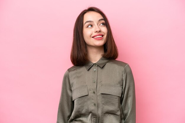 Young Ukrainian woman isolated on pink background thinking an idea while looking up