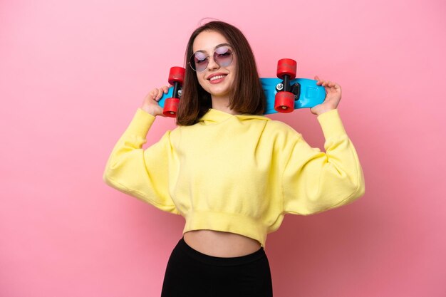 Young Ukrainian woman isolated on pink background with a skate with happy expression
