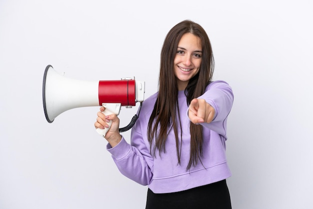 Young Ukrainian woman isolated on white background holding a megaphone and smiling while pointing to the front