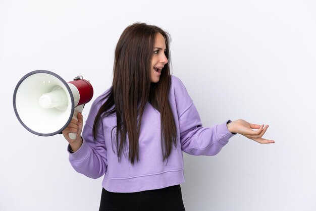 Young Ukrainian woman isolated on white background holding a megaphone and with surprise facial expression