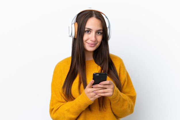 Young Ukrainian woman isolated on white background listening music with a mobile and looking front