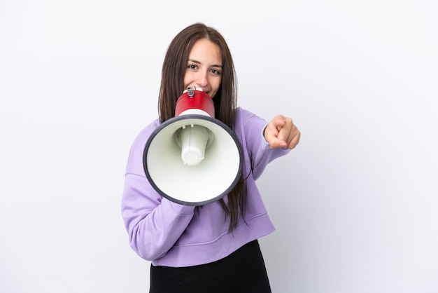 Young Ukrainian woman isolated on white background shouting through a megaphone to announce something while pointing to the front