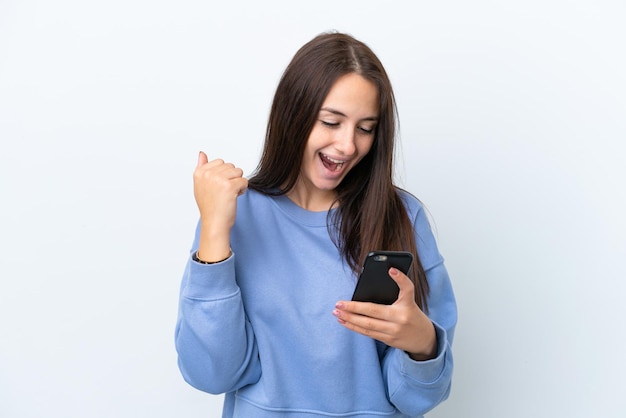 Young Ukrainian woman isolated on white background using mobile phone and doing victory gesture