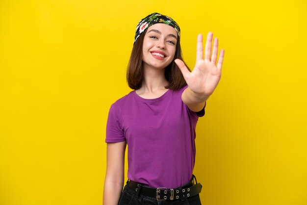 손가락으로 다섯을 세는 노란색 배경에 고립 된 젊은 우크라이나 여자