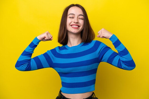 Young Ukrainian woman isolated on yellow background doing strong gesture