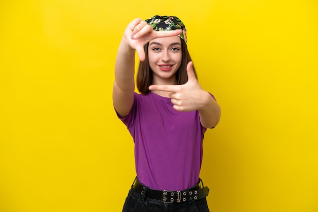 Young Ukrainian woman isolated on yellow background focusing face Framing symbol