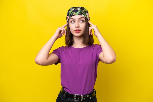 Young Ukrainian woman isolated on yellow background having doubts and thinking