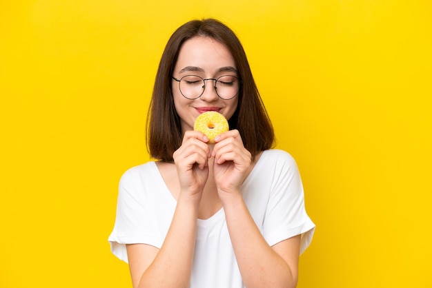 Giovane donna ucraina isolata su sfondo giallo che tiene una ciambella