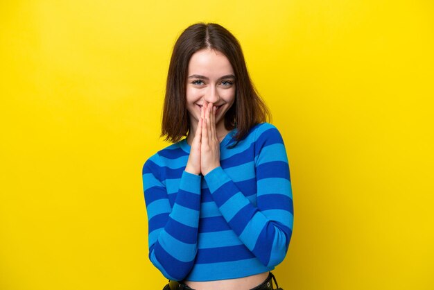 Young ukrainian woman isolated on yellow background keeps palm together person asks for something