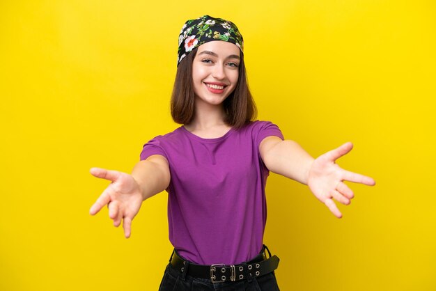 Young Ukrainian woman isolated on yellow background presenting and inviting to come with hand