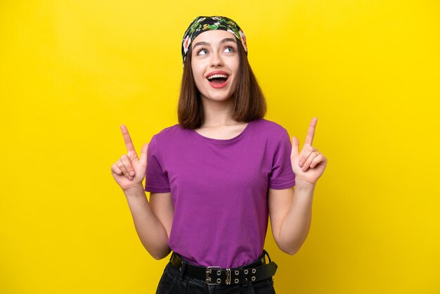 Young Ukrainian woman isolated on yellow background surprised and pointing up