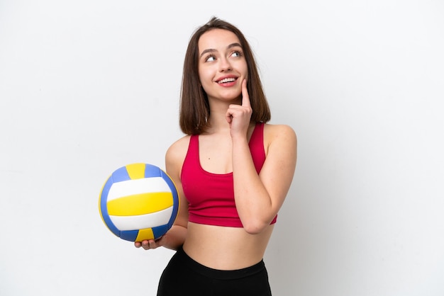 Молодая украинка играет в волейбол на белом фоне, думая об идее, глядя вверх
