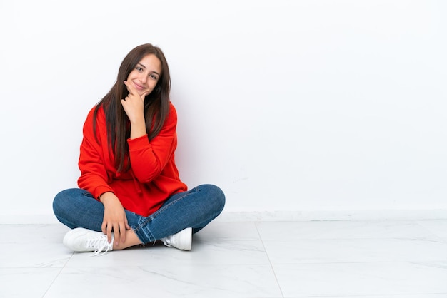Young Ukrainian woman sitting on the floor isolated on white background smiling