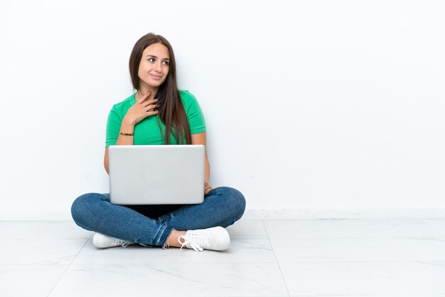 Foto giovane donna ucraina con un computer portatile seduto sul pavimento guardando in alto mentre sorride