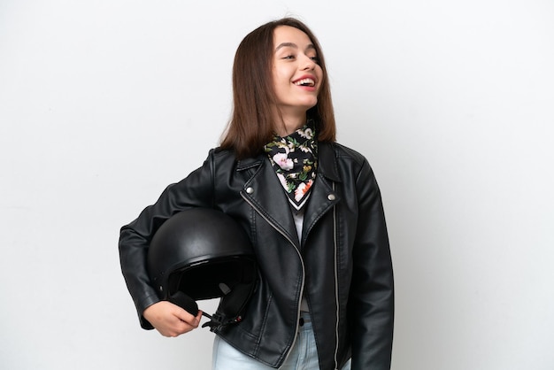 Young Ukrainian woman with a motorcycle helmet isolated on white background laughing in lateral position