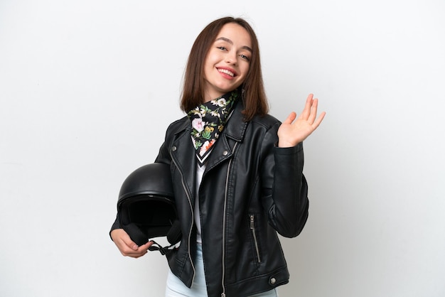 Young Ukrainian woman with a motorcycle helmet isolated on white background saluting with hand with happy expression