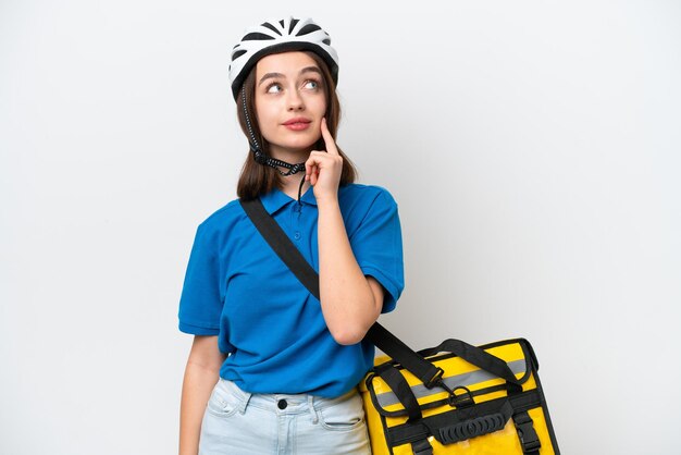 Young Ukrainian woman with thermal backpack isolated on white background thinking an idea while looking up