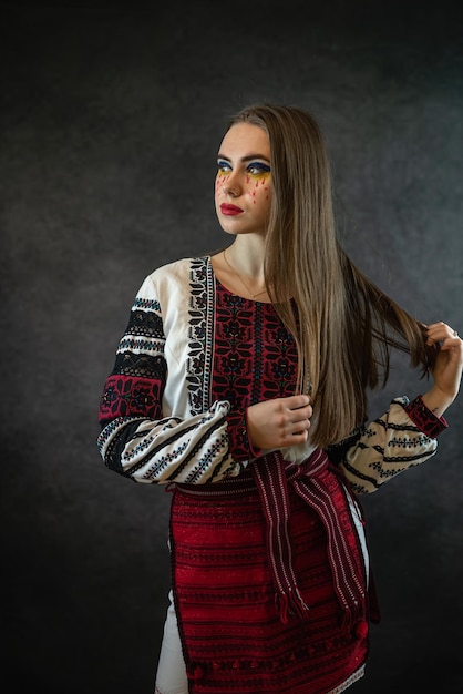젊은 우크라이나 여성은 스튜디오 패션 천에서 자수와 포즈의 전통 의상을 입었습니다.