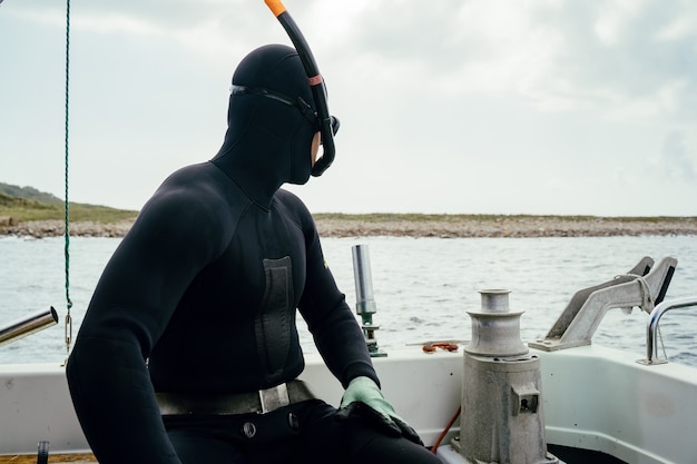 Young underwater hunter diver preparing to dive by boat