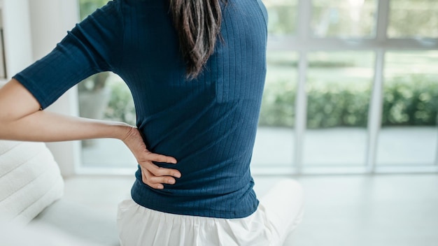 Young unhappy woman feeling discomfort because of pain in back