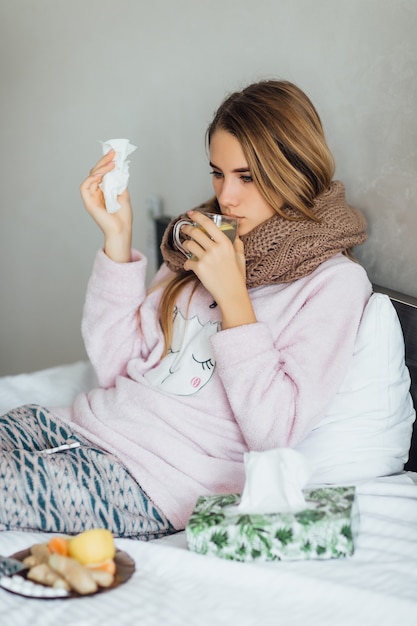 Young unhealthy woman with tea on hands feeling bad