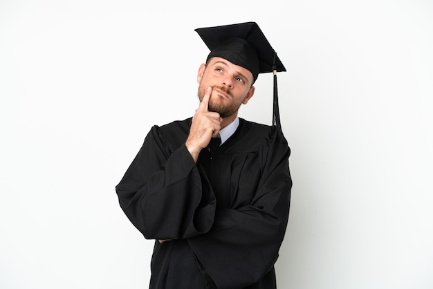 Young university Brazilian graduate isolated on white background having doubts while looking up