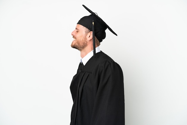 Young university Brazilian graduate isolated on white background laughing in lateral position