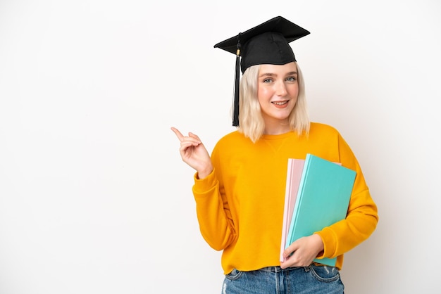 Young university caucasian woman graduate isolated on white background pointing finger to the side