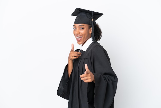 Giovane donna afroamericana laureata isolata su sfondo bianco che indica la parte anteriore e sorridente