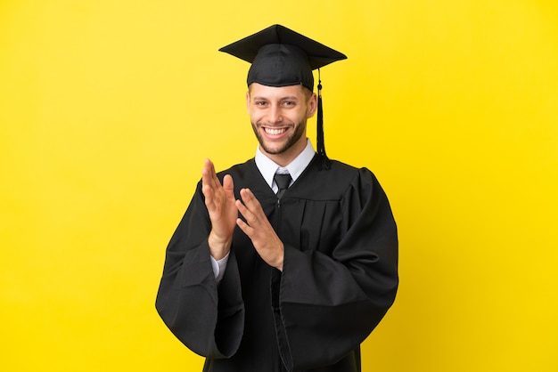 Young university graduate caucasian man isolated on yellow background applauding after presentation in a conference