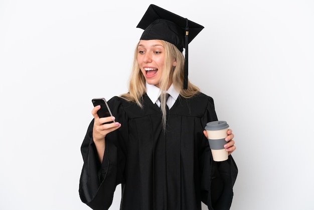 Giovane donna caucasica laureata isolata su sfondo bianco che tiene caffè da portare via e un cellulare Foto Premium