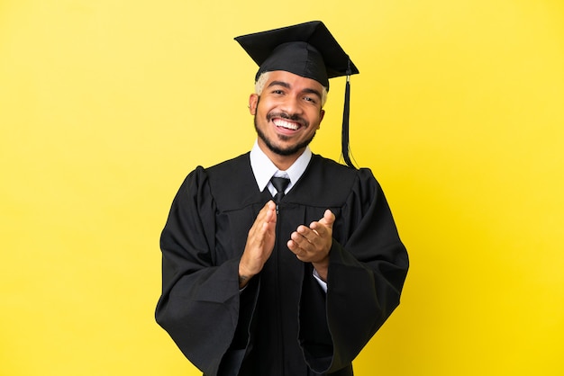 Young university graduate Colombian man isolated on yellow background applauding after presentation in a conference