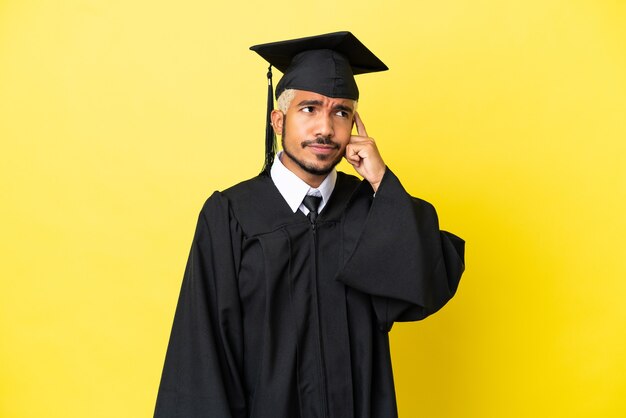 疑いを持って、混乱した表情で黄色の背景に孤立した若い大学卒業生のコロンビア人