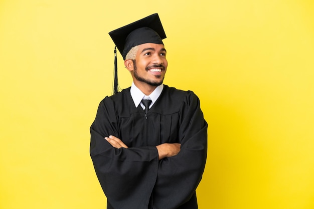 Young university graduate Colombian man isolated on yellow background looking up while smiling