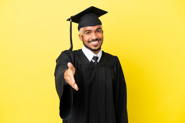 Young university graduate Colombian man isolated on yellow background shaking hands for closing a good deal