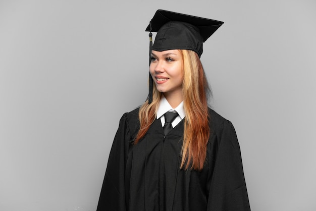 Young university graduate girl over isolated background looking side