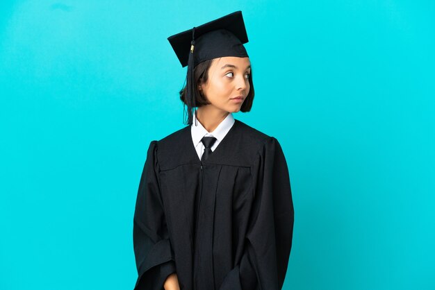 Молодая девушка выпускника университета на изолированном синем фоне. Портрет