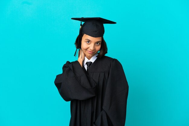 笑っている孤立した青い壁の上の若い大学卒業生の女の子