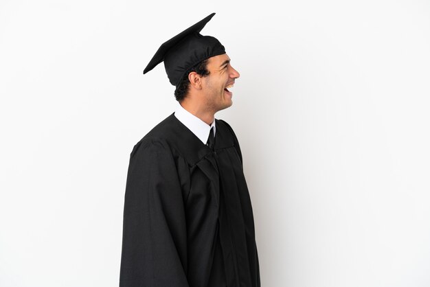 Young university graduate over isolated white background laughing in lateral position