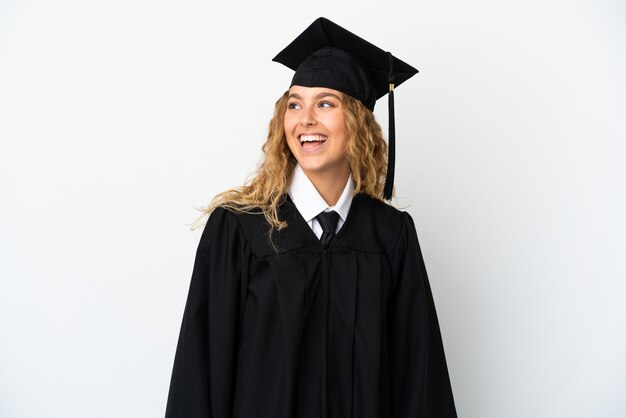 Young university graduate isolated on white background looking side