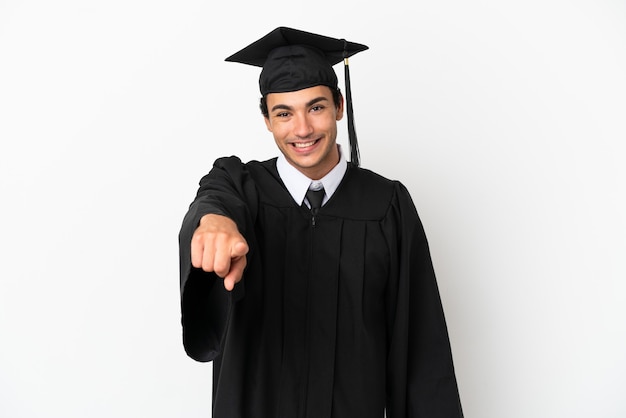 Giovane laureato su sfondo bianco isolato ti punta il dito contro con un'espressione sicura