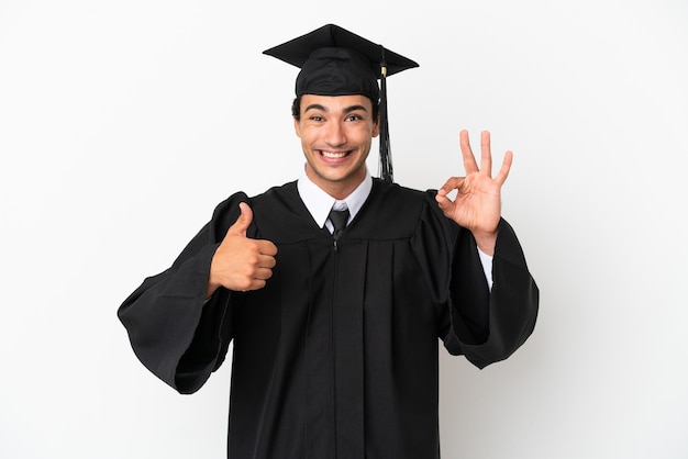 확인 표시와 제스처를 엄지손가락을 보여주는 격리 된 흰색 배경 위에 젊은 대학 졸업