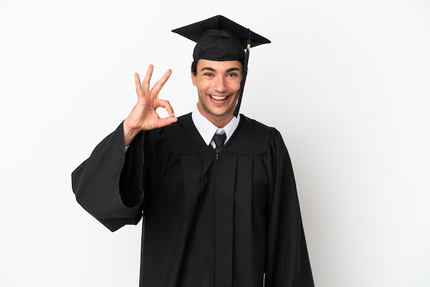 Giovane laureato su sfondo bianco isolato che mostra segno ok con le dita